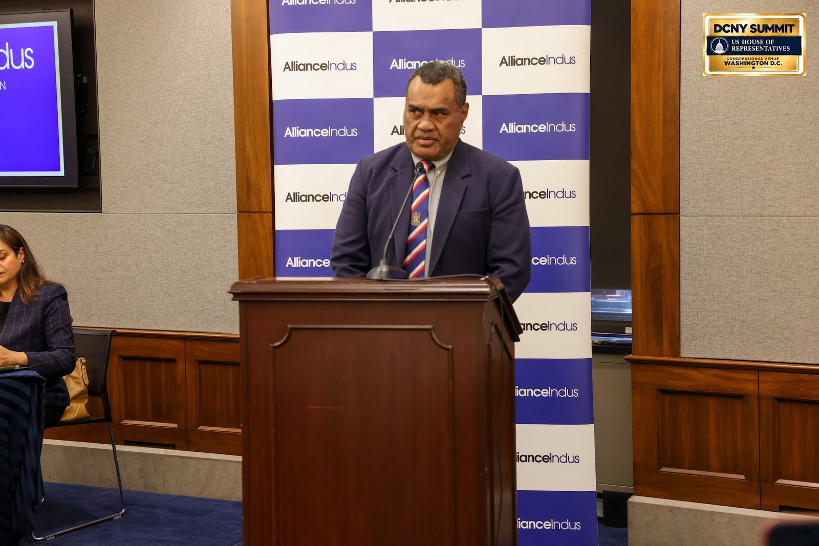 Fiji's ambassador speaks at the podium in front of an AllianceIndus backdrop