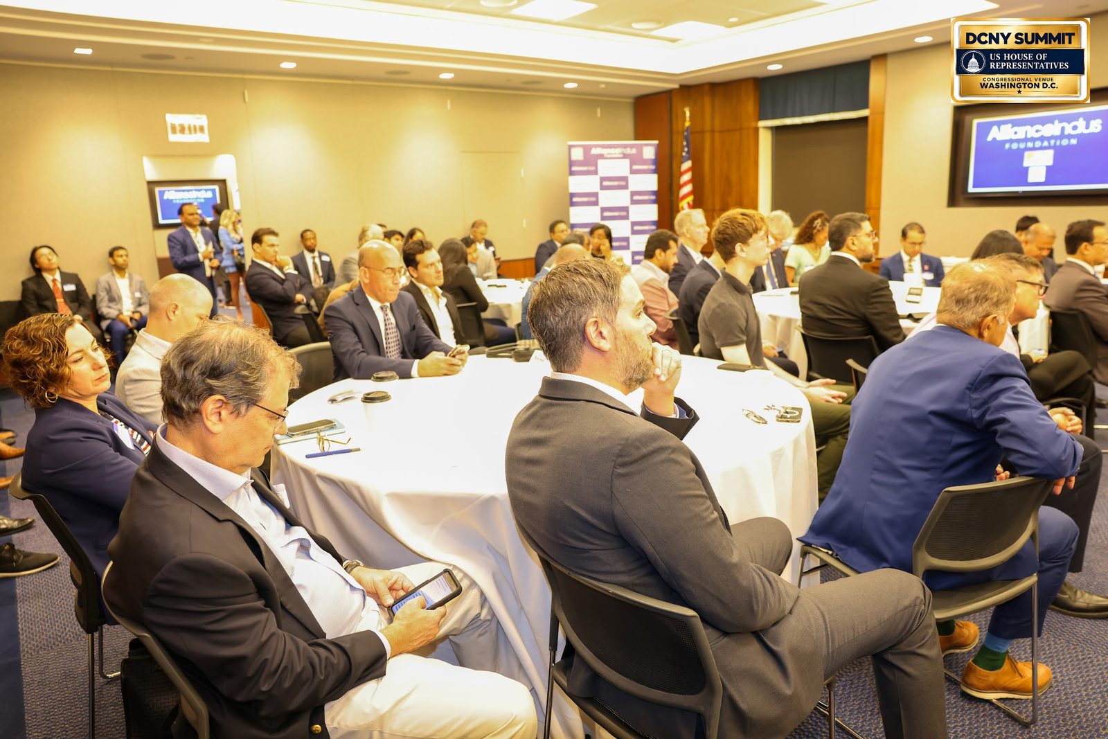 Guests seated at round tables, turned toward the front of the room