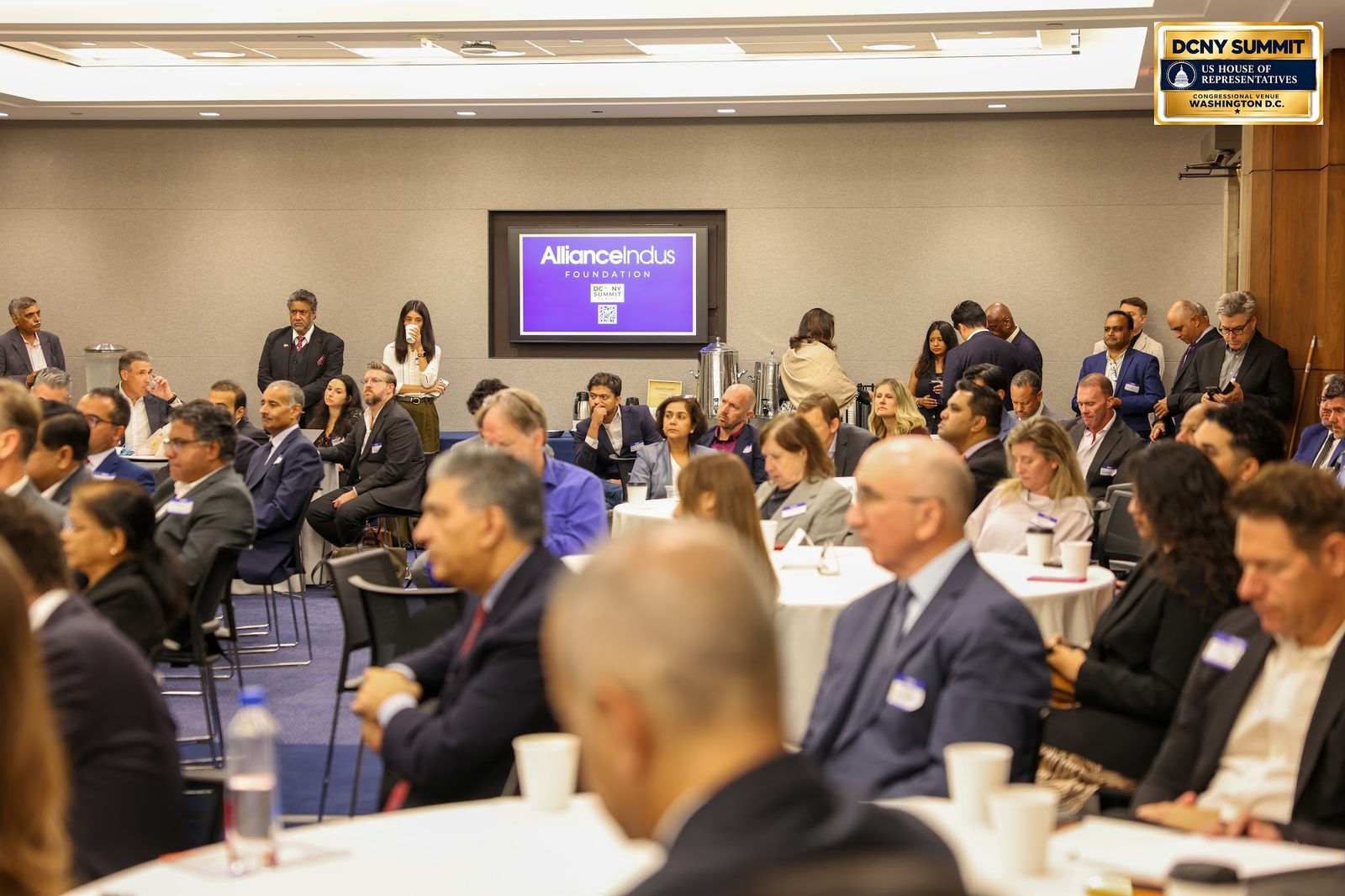 Rows of guests at tables facing a screen showing the AllianceIndus Foundation logo