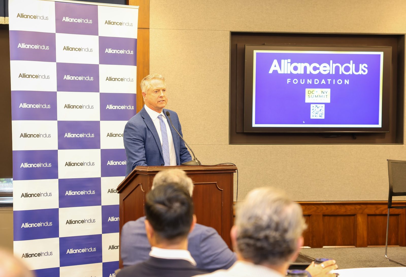 Sen. Roger Marshall speaks at a wooden podium in front of an AllianceIndus backdrop and a screen showing the foundation's logo