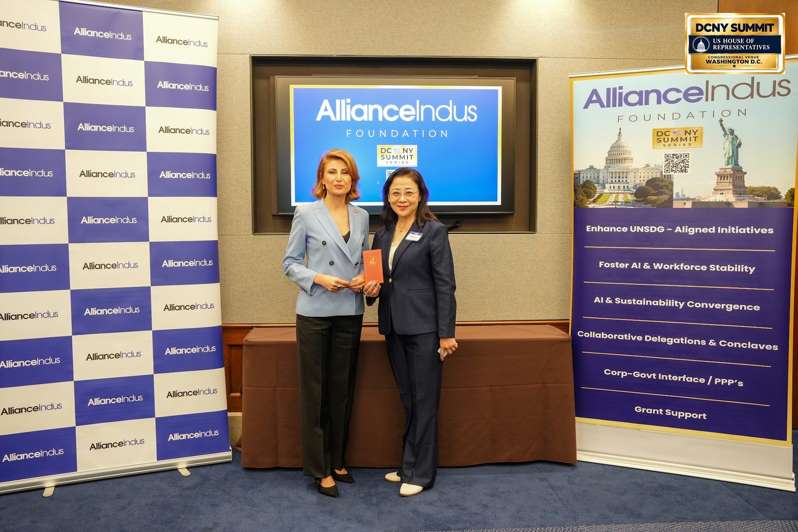 Two women pose at the AllianceIndus photo wall