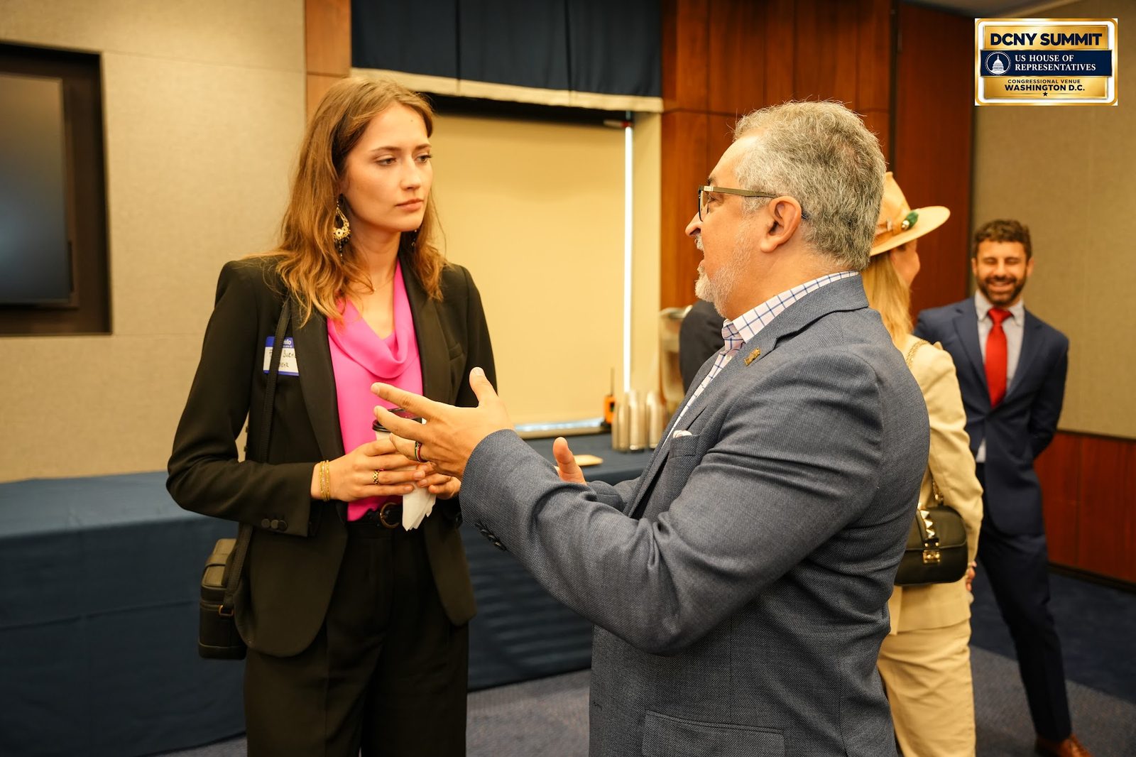 Two guests talking, one gesturing, with others in the background
