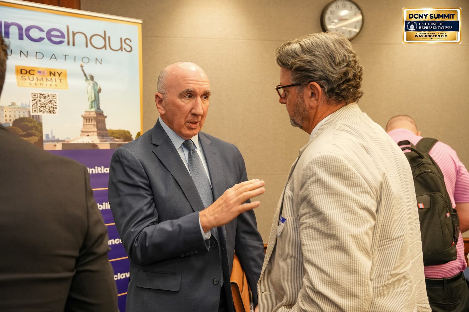 Two men in conversation in front of the AllianceIndus banner